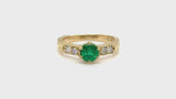 Emerald engagement ring with engraved yellow gold band and diamonds